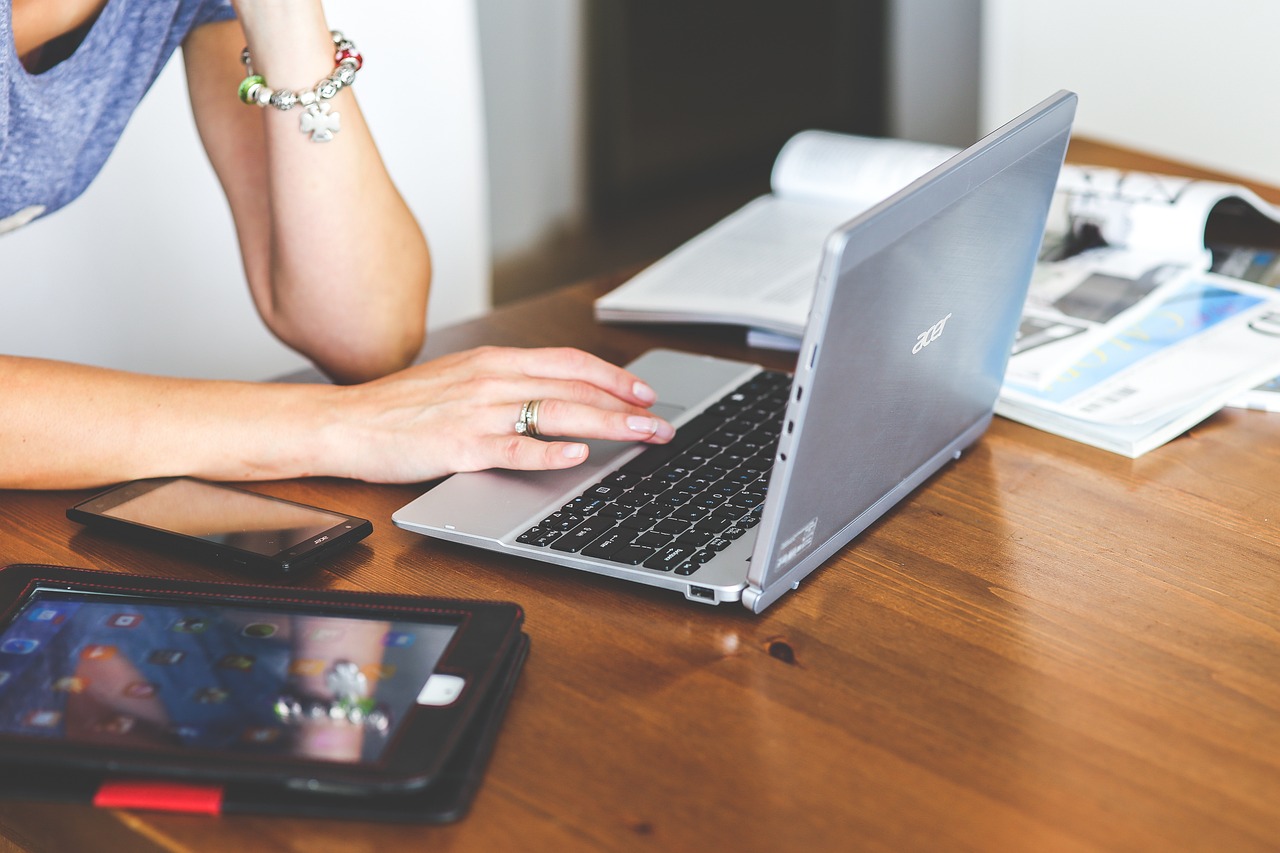 A young woman using a laptop at a desk, focused on online learning indoors.